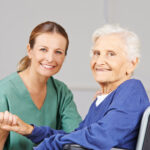 Altenpflege durch lächelnde Krankenschwester bei einer glücklichen Seniorin