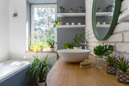 Weißes, gemütliches Badezimmer in modernem Design, mit Fenster und grünen Pflanzen.